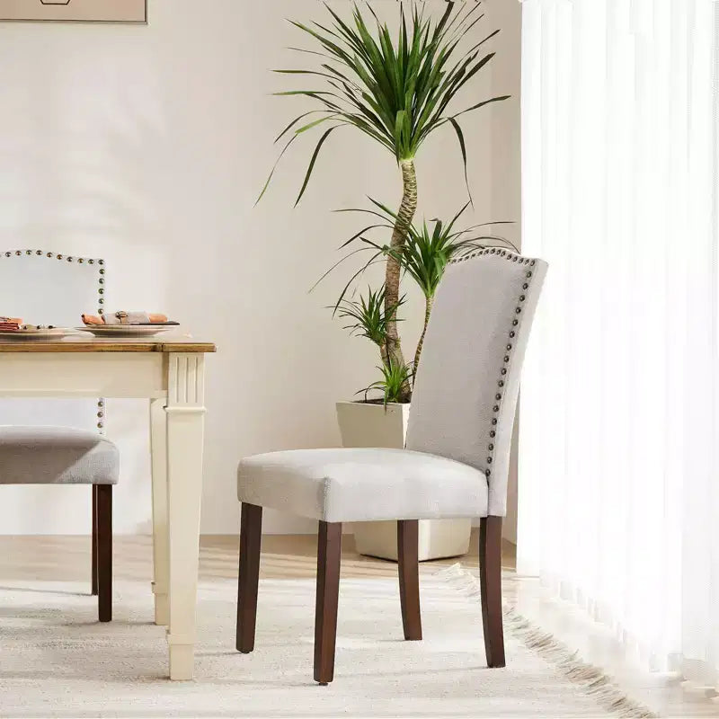 Juego de 2 sillas de comedor modernas sin brazos, tapizadas en tela, con adornos de tachuelas y patas de madera