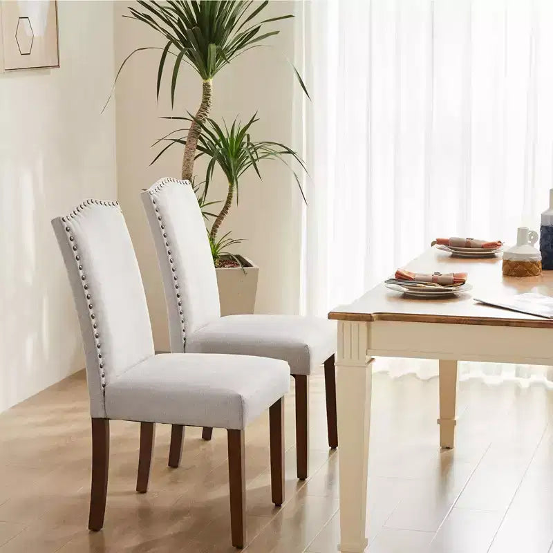Juego de 2 sillas de comedor modernas sin brazos, tapizadas en tela, con adornos de tachuelas y patas de madera